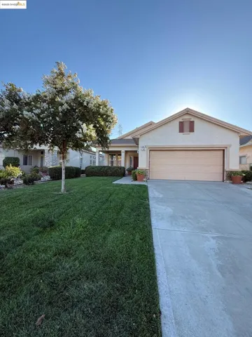 Ranch-style house with stucco siding, concrete driveway, a front lawn, an attached garage, and covered porch