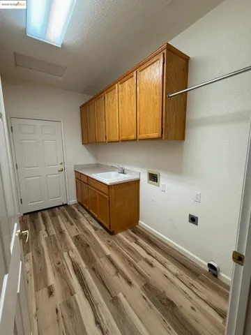 Laundry room with cabinet space, hookup for a washing machine, light wood-style flooring, a textured ceiling, and electric dryer hookup