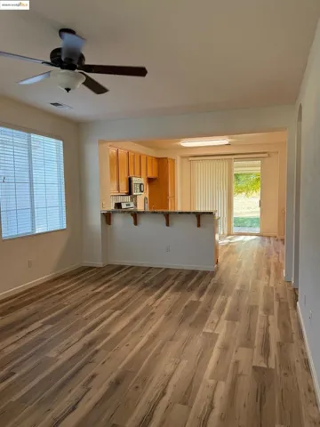 Unfurnished living room featuring dark wood-style flooring, ceiling fan, and arched walkways
