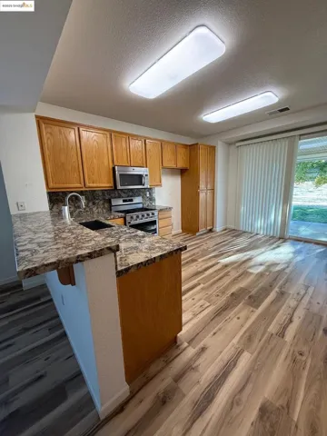 Kitchen featuring brown cabinetry, tasteful backsplash, light wood finished floors, a peninsula, and a textured ceiling