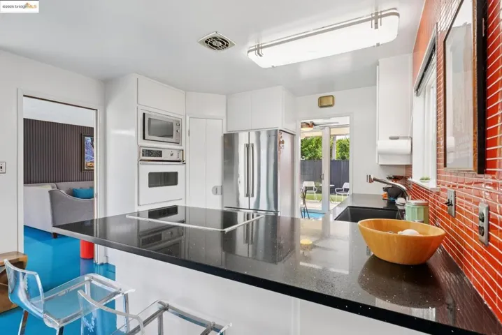 Kitchen with a kitchen breakfast bar, stainless steel appliances, a peninsula, white cabinets, and dark stone counters