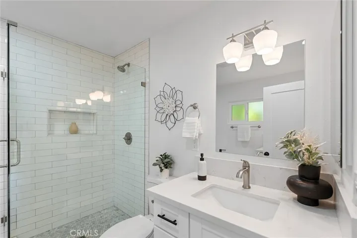 Beautiful details of quartz counters, shower shelf, and pretty lights
