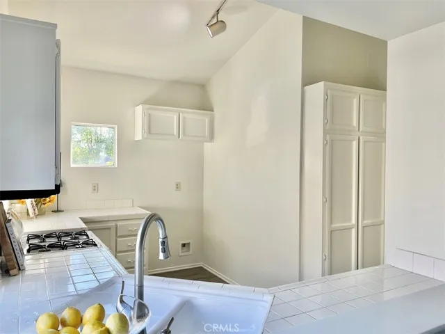 Kitchen with gas appliances and track lighting.