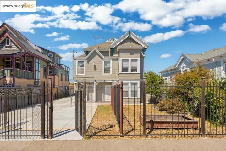 Victorian-style house with a fenced front yard, a residential view, a gate, and driveway