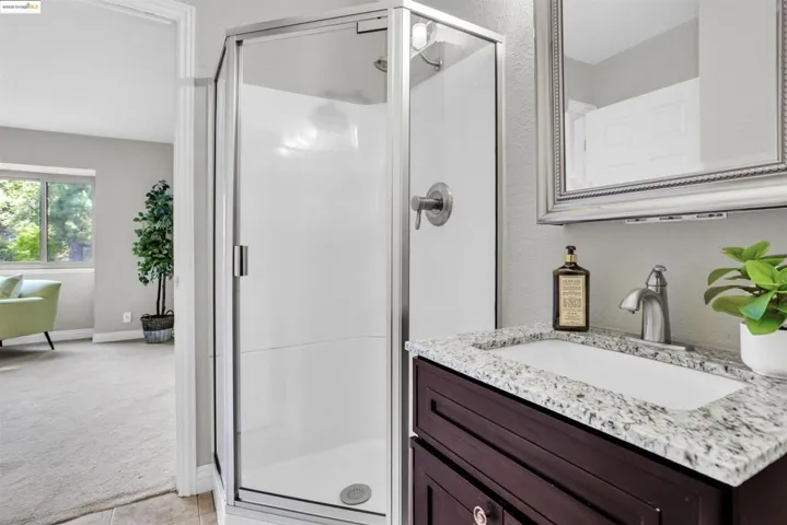 Full bath featuring a stall shower, vanity, light tile patterned floors, and a textured wall