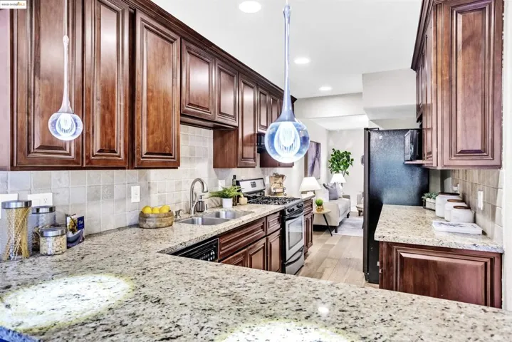 Kitchen featuring decorative backsplash, light stone countertops, dark brown cabinetry, stainless steel appliances, and recessed lighting