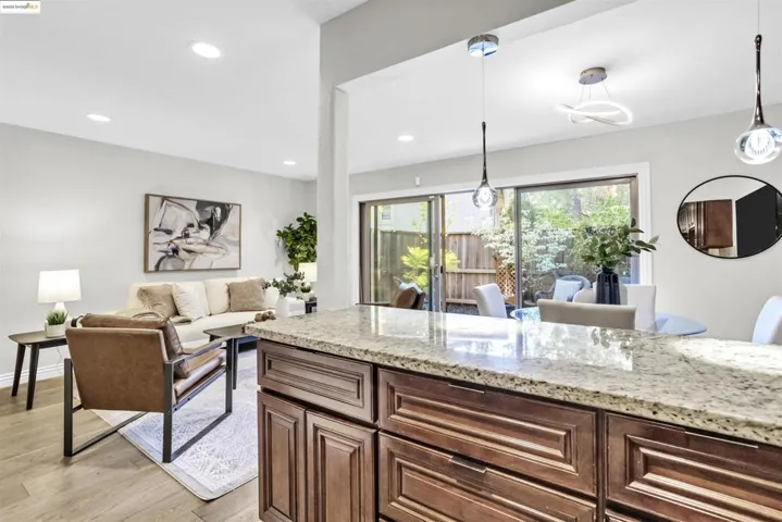 Kitchen with hanging light fixtures, light stone countertops, light wood finished floors, recessed lighting, and open floor plan