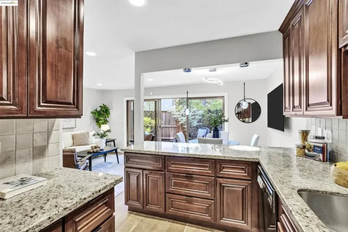 Kitchen featuring decorative backsplash, light stone countertops, recessed lighting, hanging light fixtures, and light wood-style floors