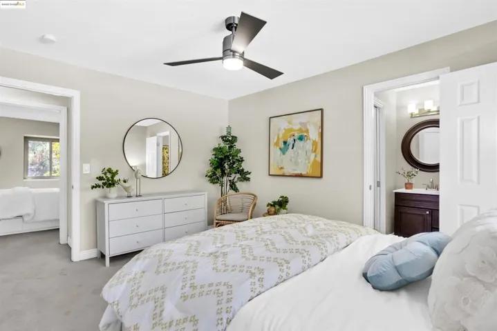 Bedroom with carpet flooring, a ceiling fan, and ensuite bath