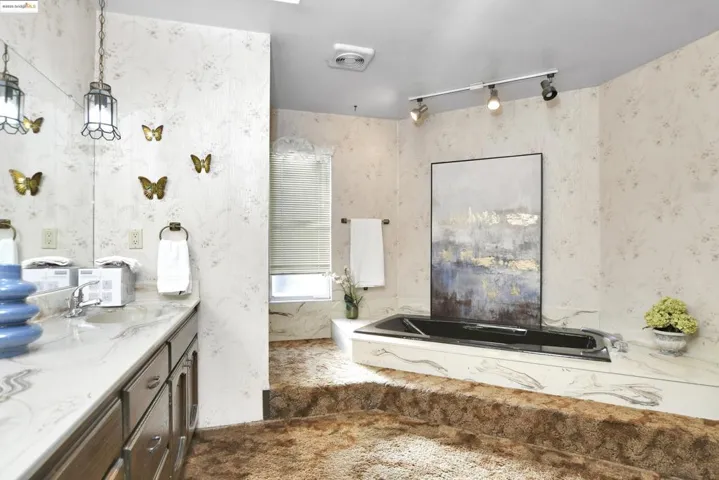 Full bath with a garden tub, vanity, wallpapered walls, and track lighting
