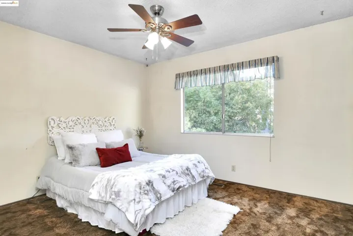 Carpeted bedroom featuring a textured ceiling and a ceiling fan
