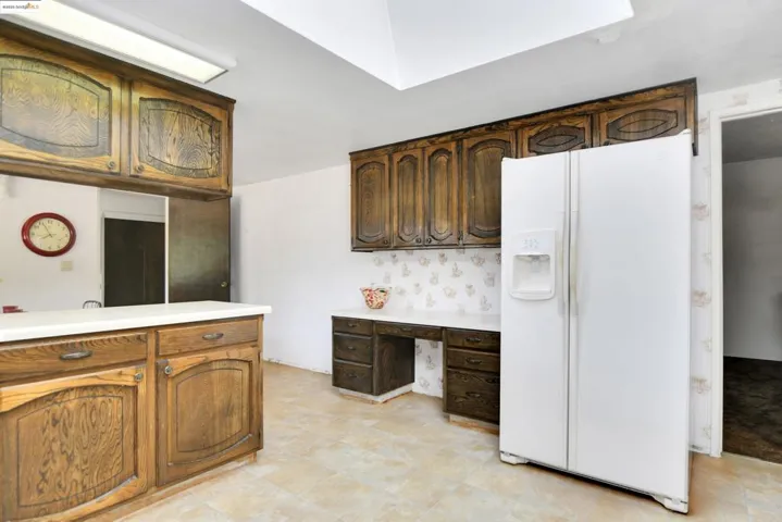 Kitchen with white fridge with ice dispenser, light countertops, and built in study area