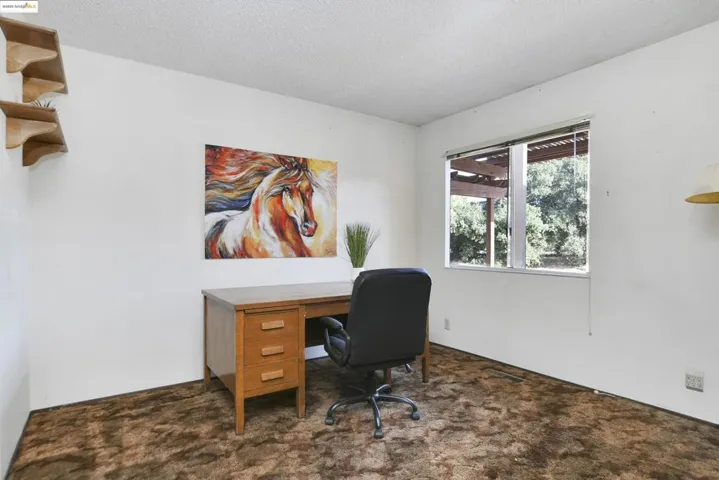 Home office featuring dark carpet and a textured ceiling