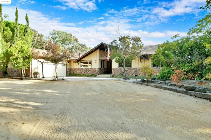 Mid-century inspired home featuring driveway, stone siding, board and batten siding, and a garage