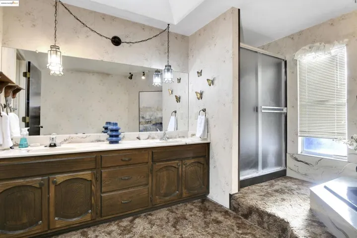 Full bath with double vanity, wallpapered walls, a shower stall, and a bath