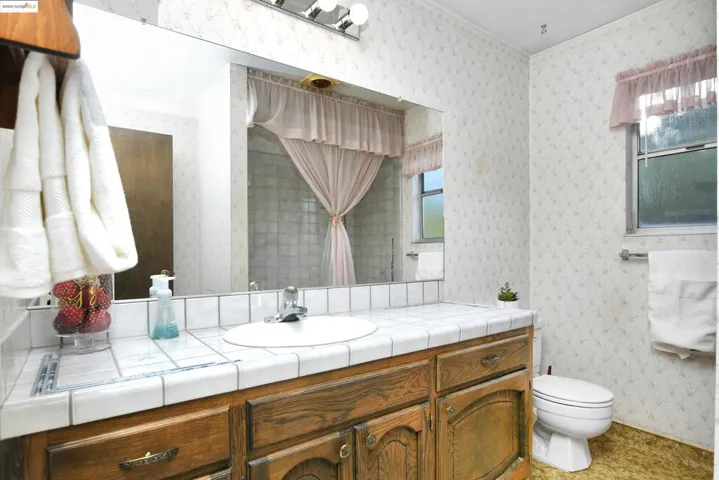 Half bathroom featuring wallpapered walls and vanity