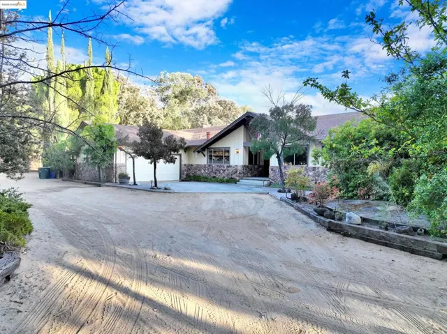 View of front of house featuring concrete driveway, a patio, a garage, and stone siding