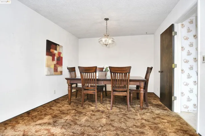Dining space featuring dark carpet, a textured ceiling, and a chandelier