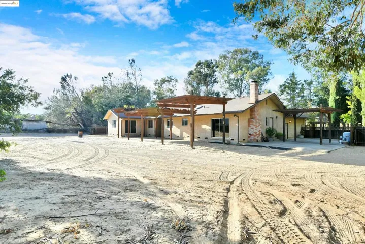 Back of house with a pergola, a patio, a chimney, and stucco siding
