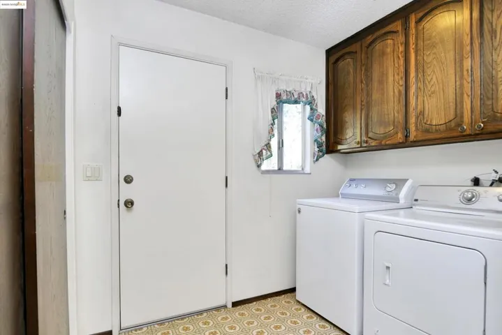 Laundry area featuring a textured ceiling, separate washer and dryer, and cabinet space