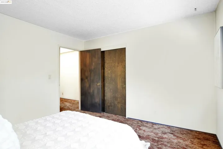 Carpeted bedroom with a textured ceiling and a closet