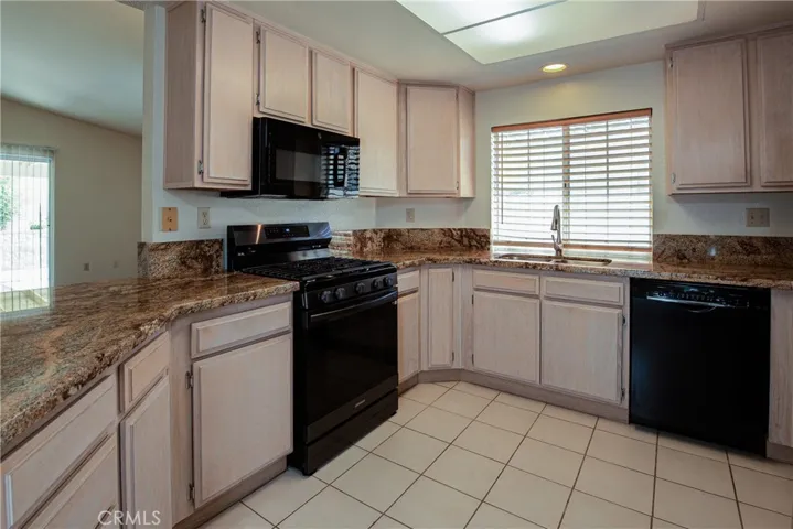 The fabulous remodeled kitchen features granite counters, tile floors, rustic cabinets, newer appliances and stainless steel sink.