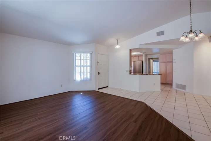 Living room with wood like laminate floors looking towards the front door, kitchen and dining room on the right.
