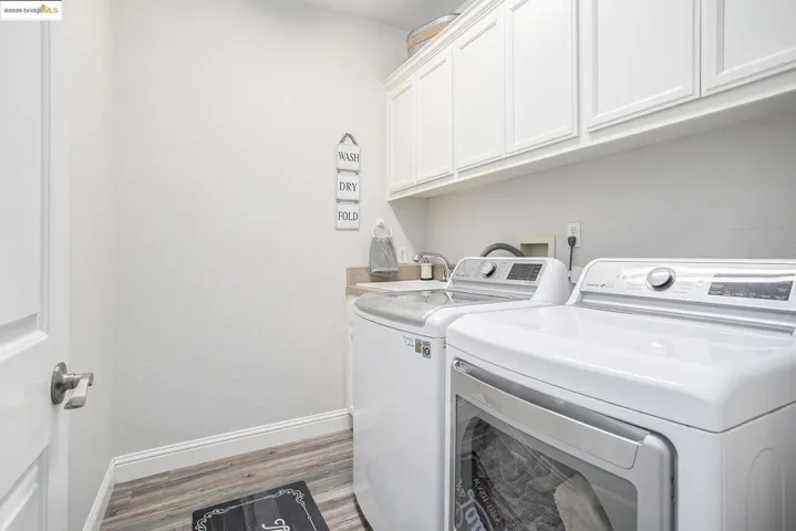 Washroom with utility sink, laminate wood finished floors, upper cabinet space, and gas or electric dryer hook-ups.