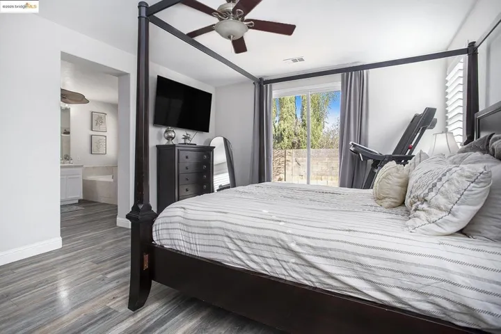 The primary bedroom with a laminate wood-style floor connects seamlessly with the primary bathroom