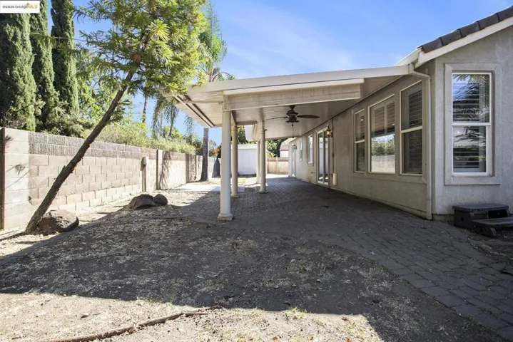 Fenced backyard with a ceiling fan and a patio