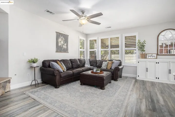 Living area featuring laminate wood-type flooring, healthy amount of natural light, and a ceiling fan