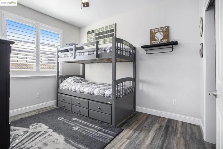 Bedroom 3 is adjacent to bedroom 2, with a ceiling fan, laminate wood-type flooring, and shutters for window covering.