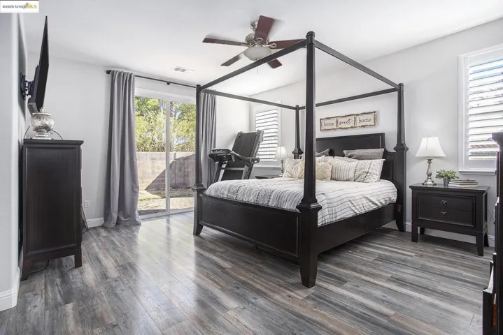 Bedroom featuring access to the exterior, laminate wood finished floors, and a ceiling fan