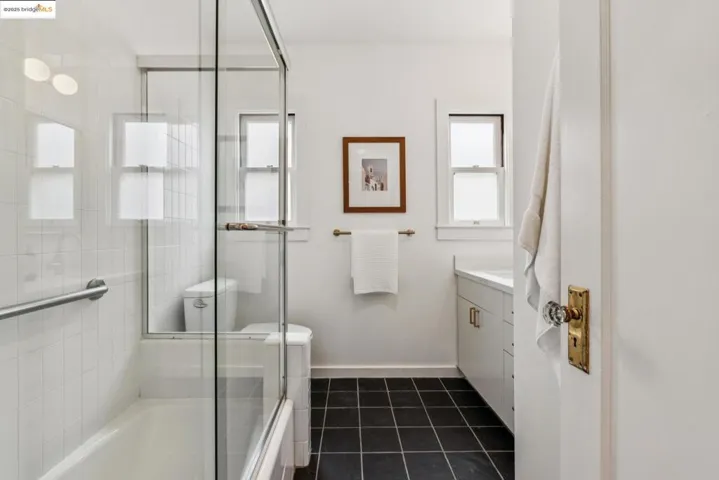 Full bathroom with vanity, dark tile patterned flooring, and shower / bath combination with glass door