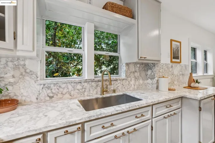 Kitchen featuring tasteful backsplash, light stone counters, and white cabinets