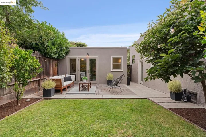 Rear view of house with stucco siding, a wooden deck, french doors, a patio area, and an outdoor hangout area