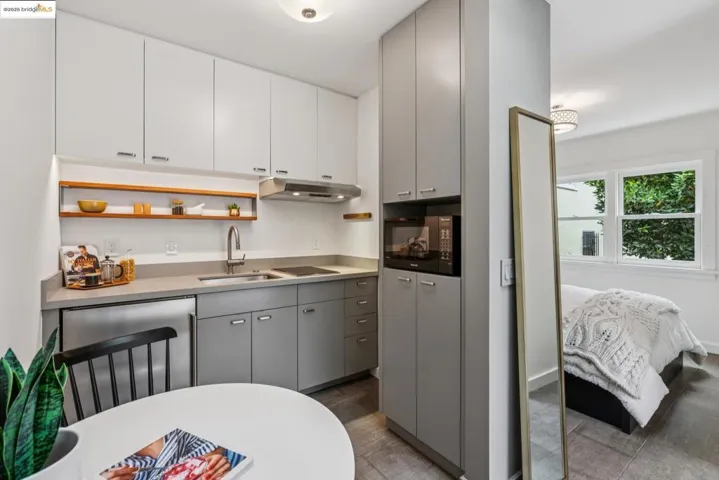 Kitchen with gray cabinets, open shelves, light countertops, under cabinet range hood, and black appliances