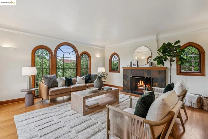 Living area with light wood finished floors, a fireplace, healthy amount of natural light, and ornamental molding