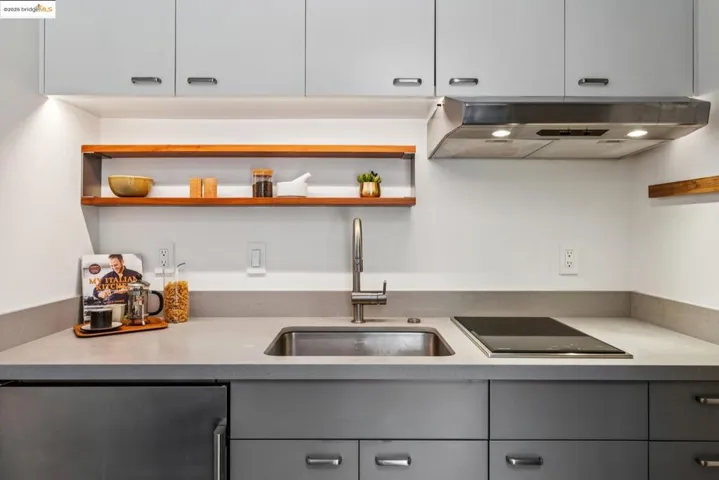 Kitchen with open shelves, gray cabinets, under cabinet range hood, and black electric cooktop