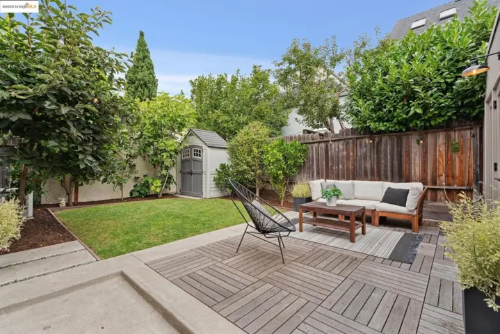 Fenced backyard featuring an outdoor living space, a storage shed, a wooden deck, and a patio area
