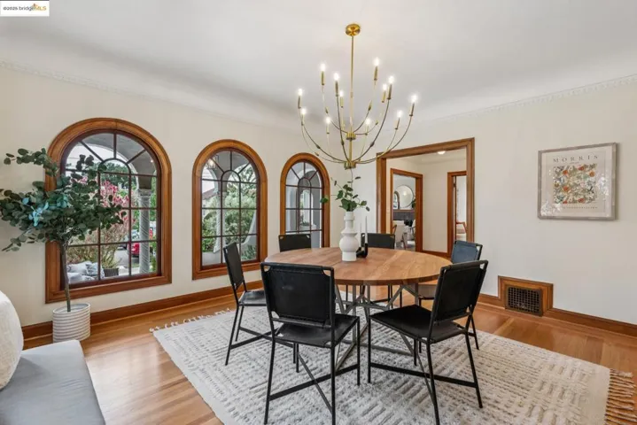 Dining space with ornamental molding, a chandelier, and light wood-style flooring