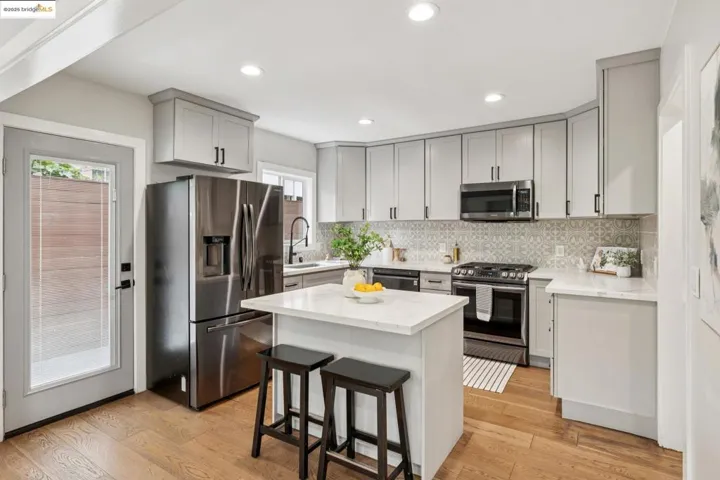 Kitchen featuring stainless steel appliances, light wood-type flooring, backsplash, a center island, and recessed lighting