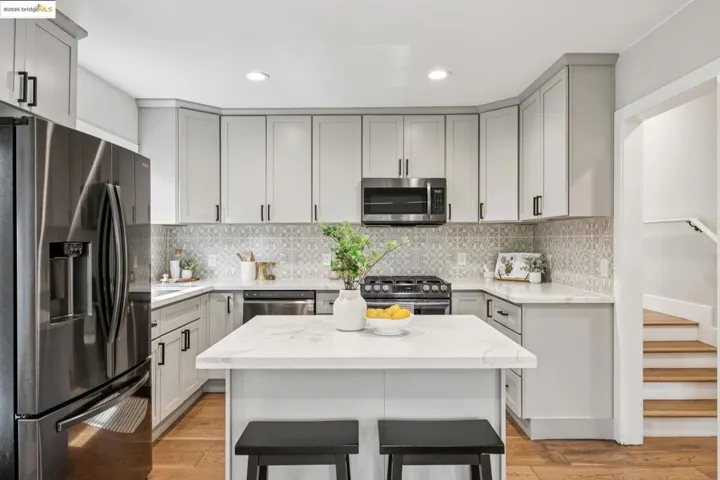Kitchen featuring appliances with stainless steel finishes, decorative backsplash, light stone counters, a kitchen breakfast bar, and light wood-type flooring