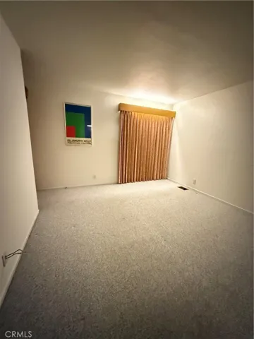 Bedroom two with curtains covering the sliding glass door. Additional door to the decks on left side.