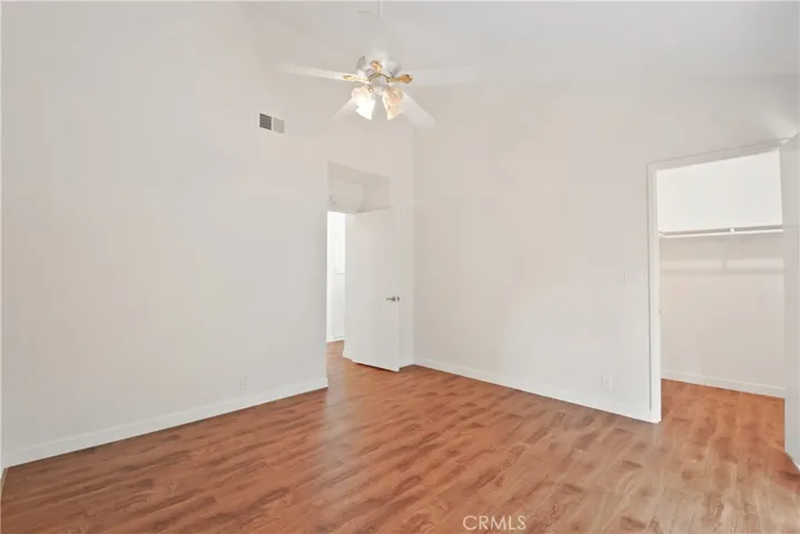 Another view of the back bedroom, with decorative ceiling fan, newly installed laminate flooring and walk-in closet