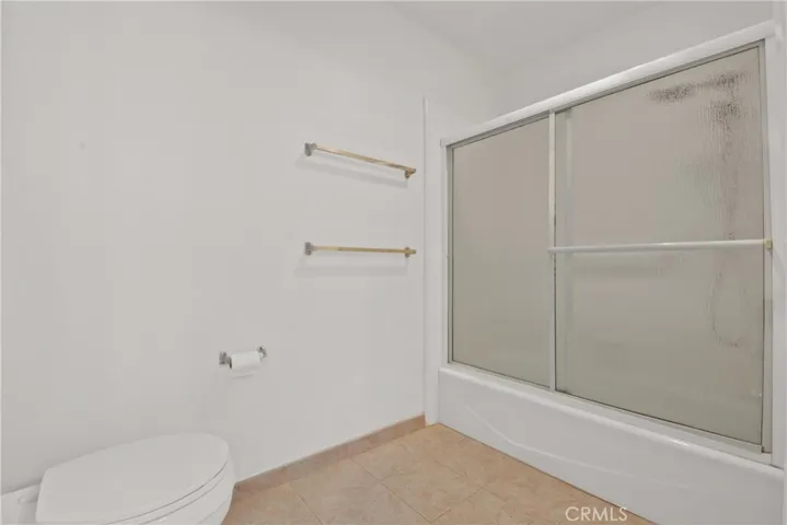 Primary bathroom with bathtub with overhead shower, ceramic tile flooring