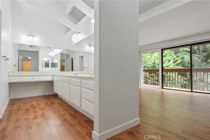 Upstairs primary dressing room with  double sinks, newly installed laminate flooring, and cathedral ceilings