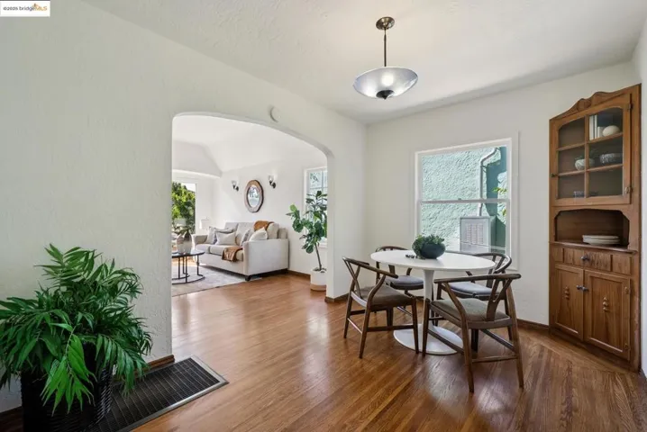 Dining room featuring arched walkways, dark wood finished floors, vaulted ceiling, and a textured wall