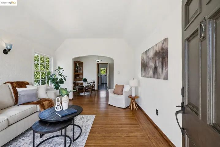Living area with arched walkways, dark wood-style floors, and vaulted ceiling