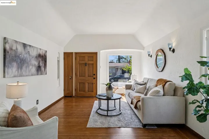 Living room featuring lofted ceiling, wood finished floors, and a textured wall